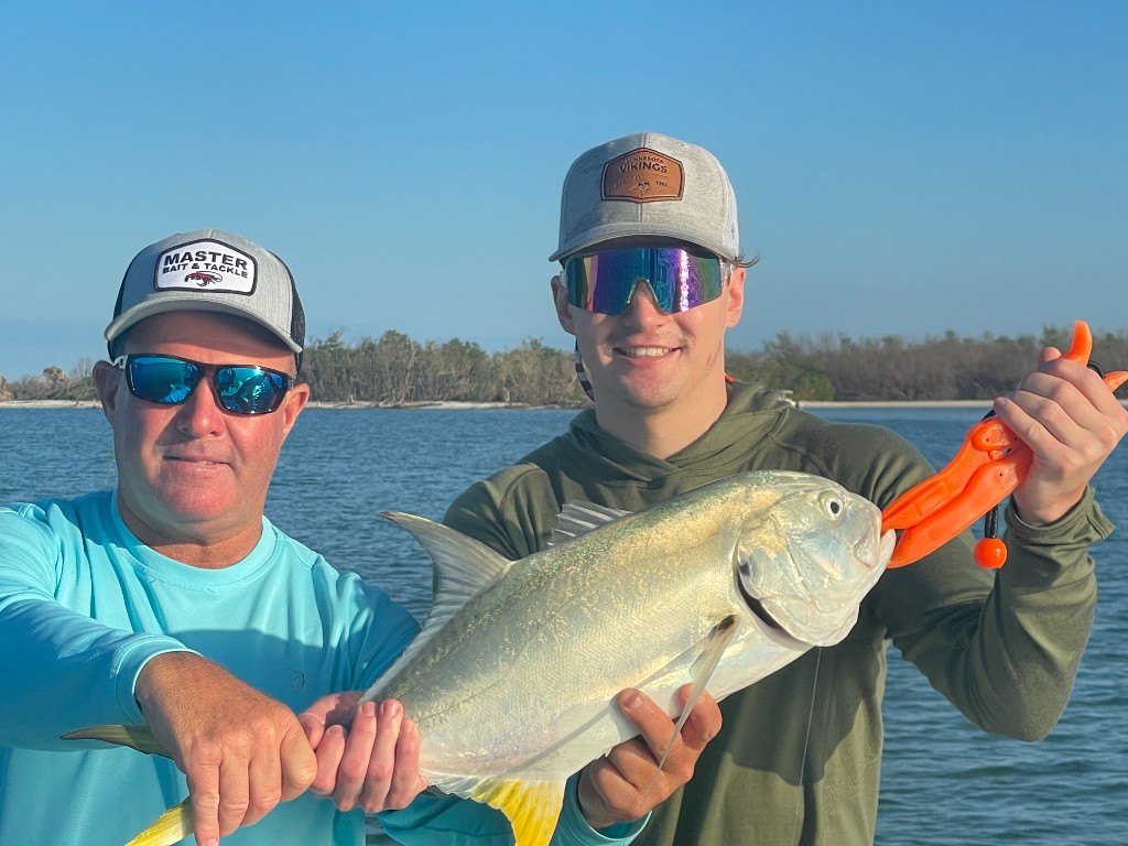 Two anglers with a jack crevalle on a boat