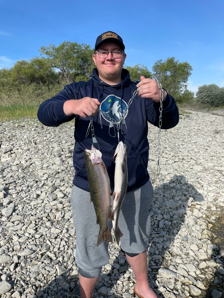 Angler with trout on a rocky riverbank